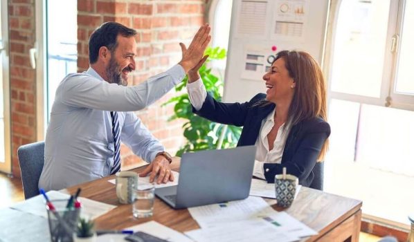 Two middle age business workers smiling happy and confident. Working together with smile on face hand giving high five at the office.