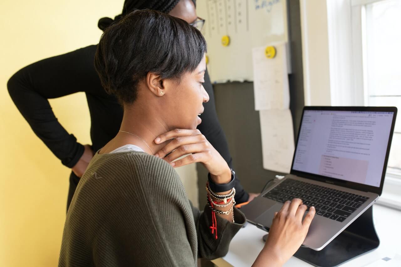 woman in a grey sweater working on a laptop, finishing tasks 