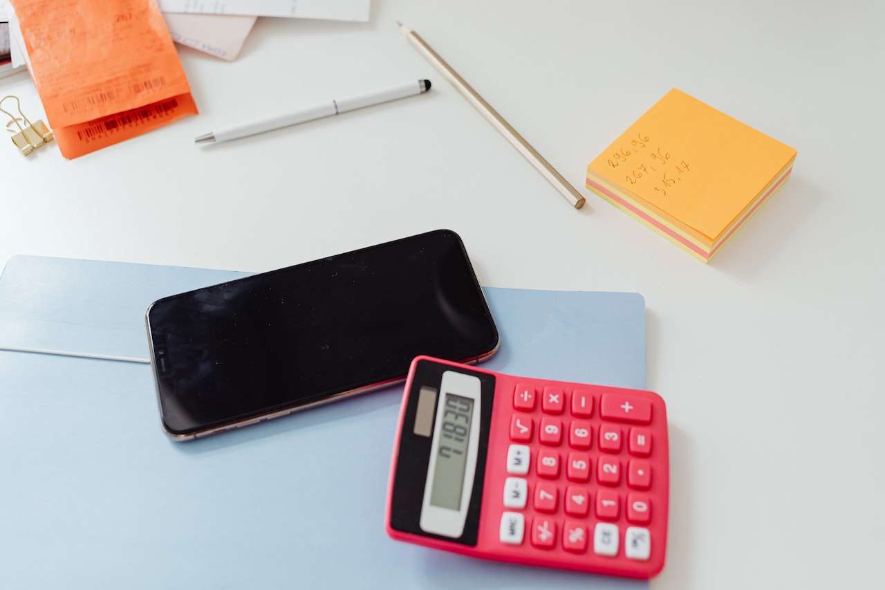 A Calculator Beside the Cellphone on a White Surface CMMS software costs