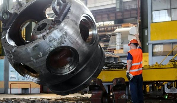 Man Standing in Front of Gray Metal Machine Part